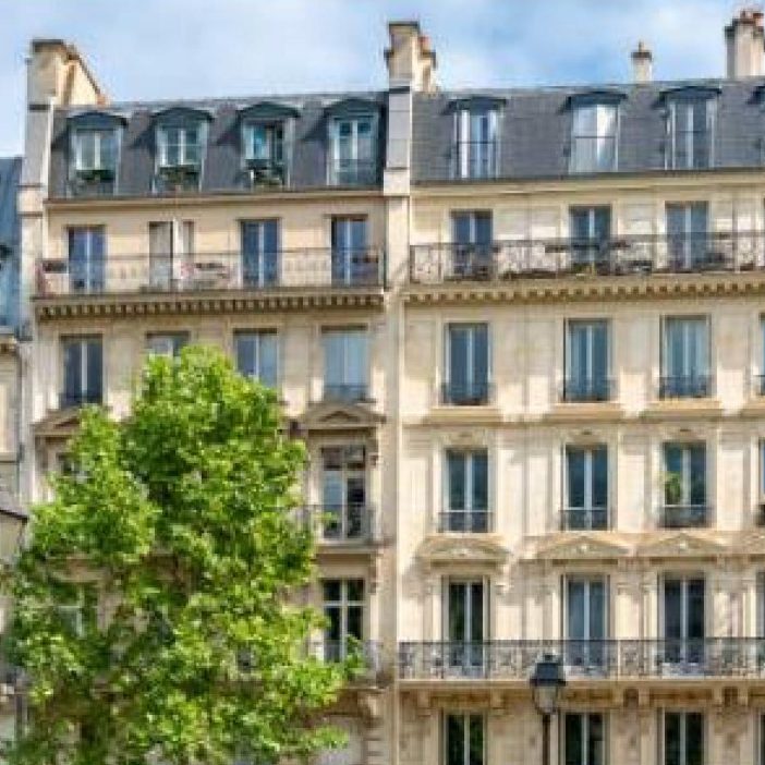 KITAROLL-BATIMENT ACHAT IMMEUBLE Bâtiment haussmannien avec balcons et fenêtres, entouré d'un arbre.